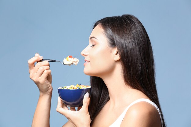 Young woman eating oatmeal on blue