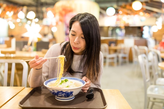 Young woman eating ramen in restaurant