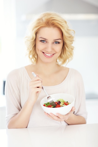 young woman eating salad in the kitchen