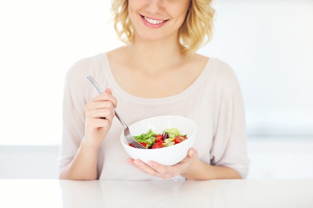 young woman eating salad in the kitchen