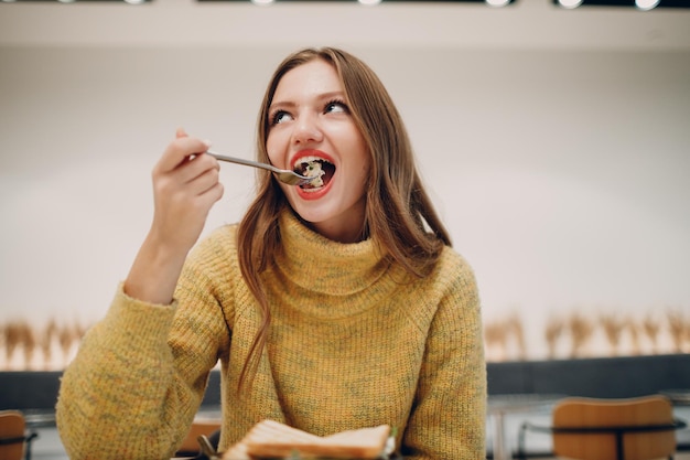 Фото Молодая женщина ест сэндвич в крытом кафе