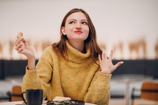 Young woman eating sandwich at indoor cafe