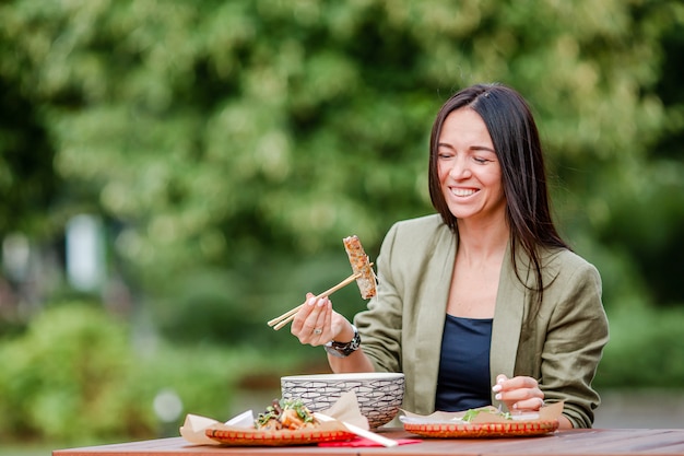 Young woman eating take away noodles on the street