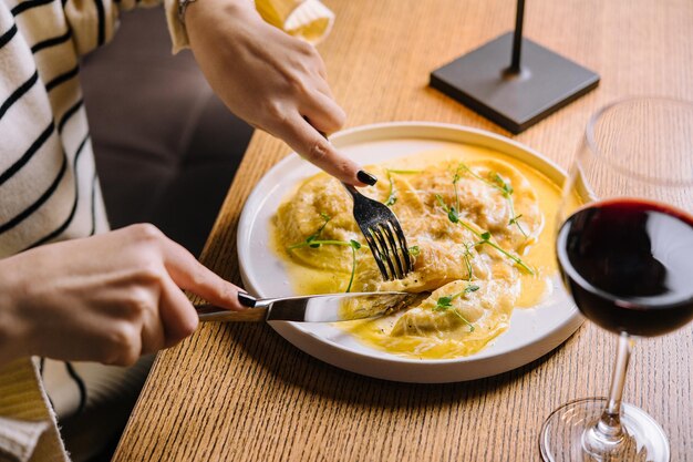 Young woman eating tasty ravioli in cafe