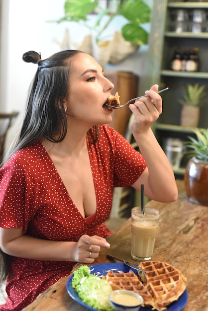 Young woman eating waffles in a coffee shop