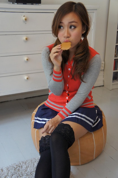 Young woman eating while sitting at home