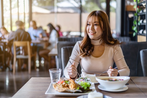 Young woman eating with food in restaurant