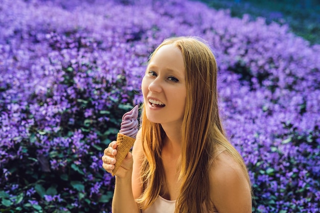 Young woman eats lavender ice cream on a lavender field background