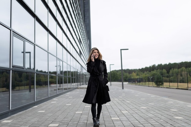 Young woman economist talking on the phone while walking down the street near the building of the