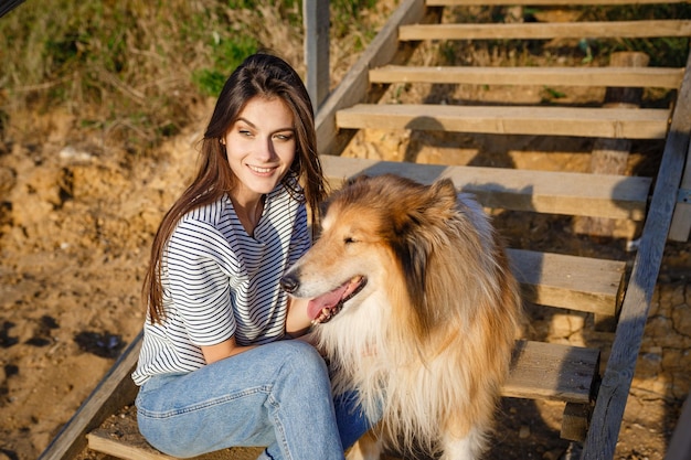 A young woman and an elderly dog walk in the countryside on a summer evening. A lady and her faithful friend from childhood a collie dog