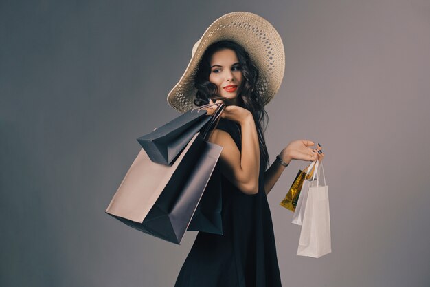 Giovane donna in elegante abito nero e cappello estivo