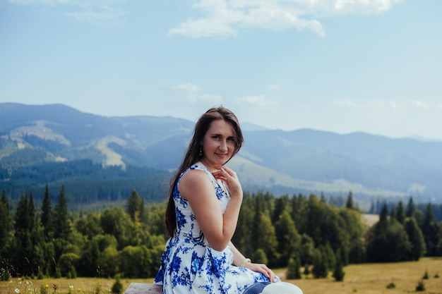 Young woman in elegant dress resting on the bench in the mountains