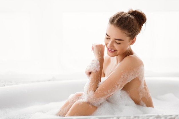 Молодая женщина наслаждается ванной с пеной и расслабляется