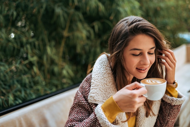 屋外のコーヒーを楽しむ若い女性。閉じる。