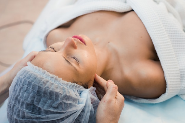 Young woman enjoying facial at spa salon