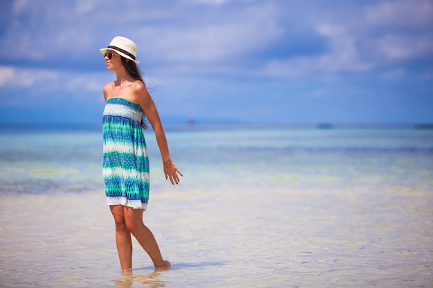Giovane donna che gode della vacanza su una spiaggia bianca e tropicale al giorno soleggiato