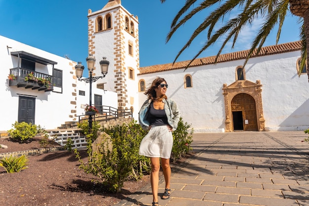 Una giovane donna che si gode le vacanze accanto alla chiesa bianca di betancuria