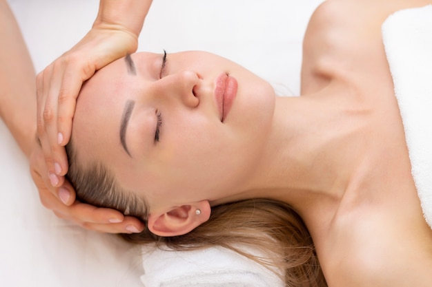 Young woman enjoying massage in spa salon. Face massage. Closeup of young woman getting spa massage treatment at beauty spa salon.