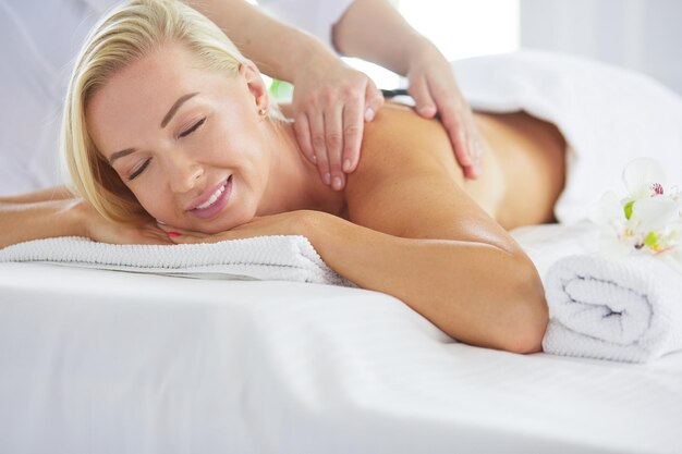 Photo young woman enjoying massage in spa salon