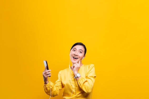 Young woman enjoying music against yellow background