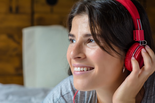 Young woman enjoying music on bed.