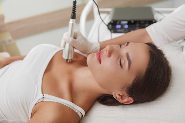 Young woman enjoying skincare treatment by professional cosmetologist