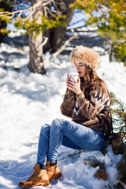 冬の雪に覆われた山々を楽しむ若い女性