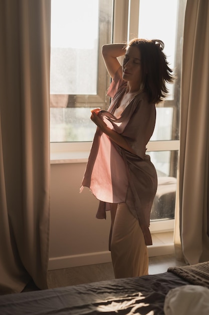 Young woman enjoying sunny morning on bedroom wakeup and wellness concept