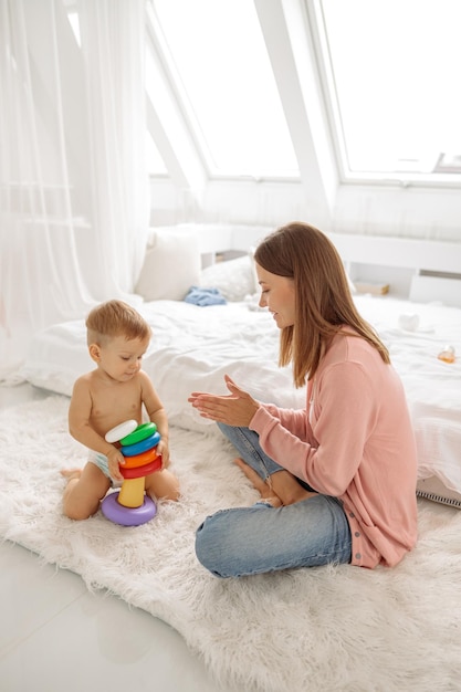 Young woman enjoying time with her kid while playing