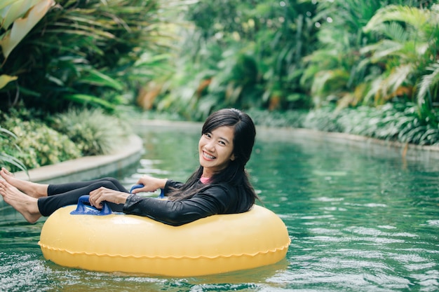 Young woman enjoying tubing at lazy river pool