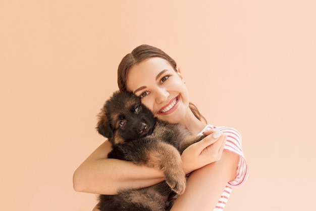 Young woman enjoys hugging a small cute puppy