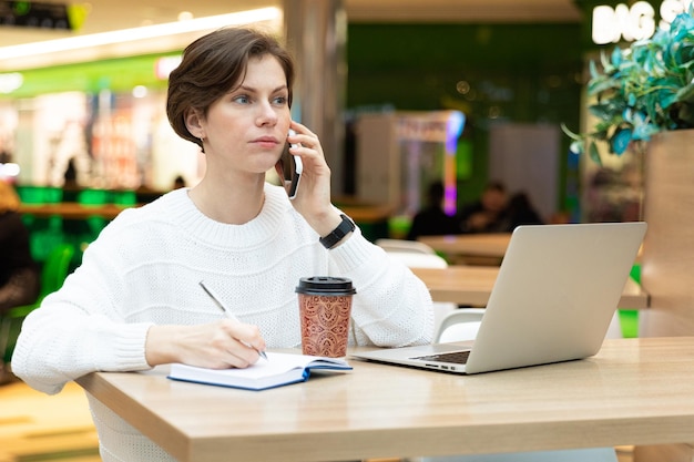 Молодая женщина-предприниматель работает на ноутбуке в кафе
