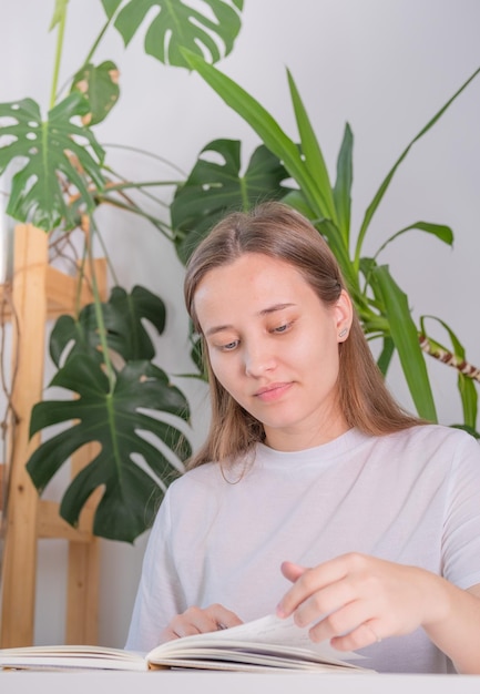 A young woman of european appearance does homework at school\
university the girl diligently studies at home at a white table\
photography in light shades in a home interior