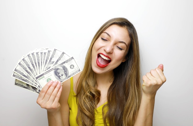 Photo young woman in excited winning pose, holding dollar notes