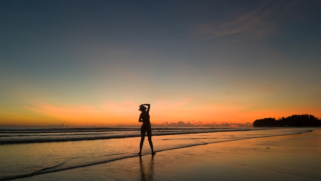 Photo young woman exercising on the beach at beautiful sunset