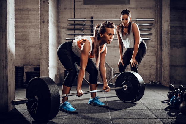 女性のパーソナルトレーナーとジムで運動している若い女性。