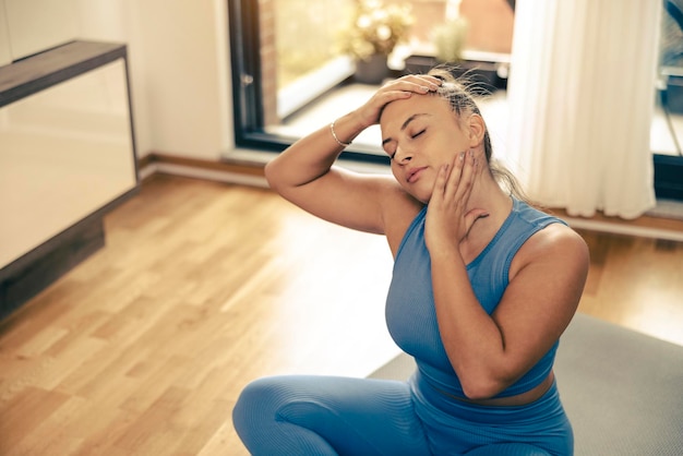 Young woman exercising at home in the morning. She is doing stretching workout.