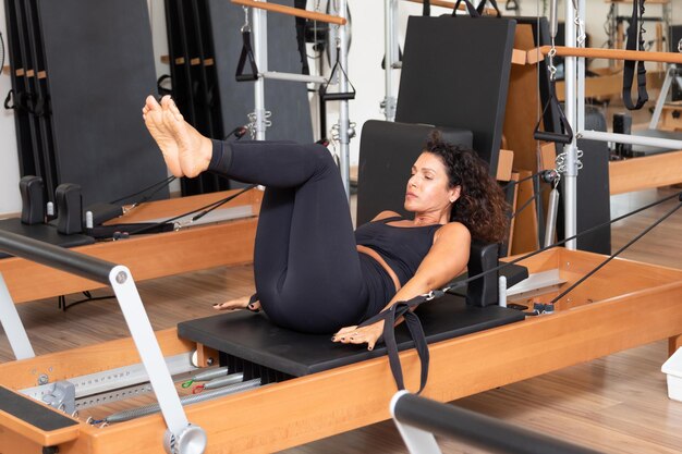 Young woman exercising on pilates reformers beds