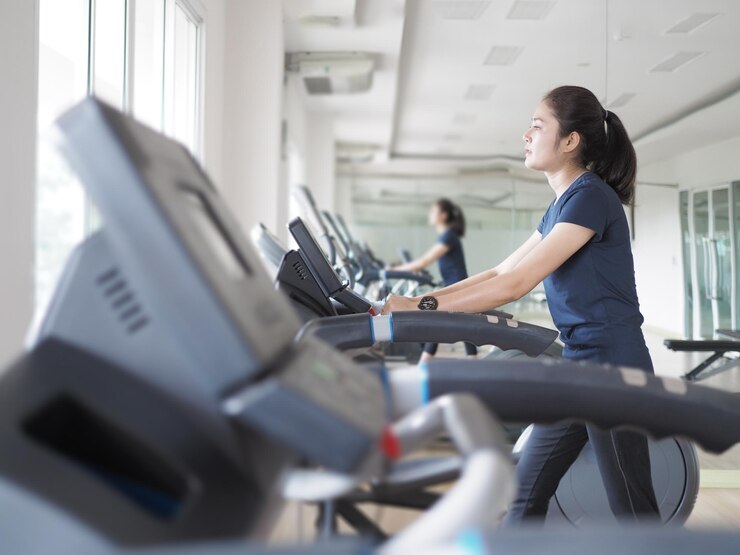 Photo 体育館でトレードミルで運動する若い女性