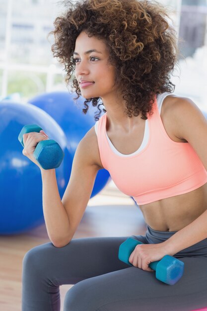 Young woman exercising with dumbbells in gym