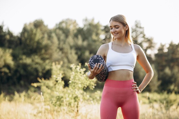 Giovane donna che esercita yoga nella foresta con attrezzatura a rullo