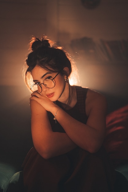 Young woman in eyeglasses looking at camera  in a cozy living room