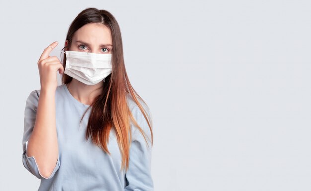 Young woman in face medical surgery mask. Coronavirus Protection, covid-19, virus, flu, could Concept. Wears, removes a medical mask.