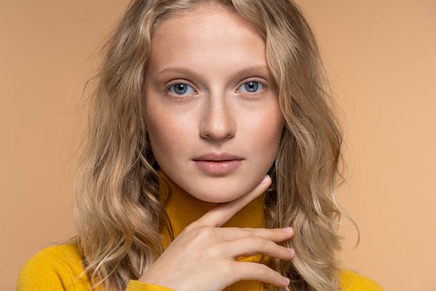 Young woman face with blue eyes, curly natural blonde hair and eyebrows, has no makeup