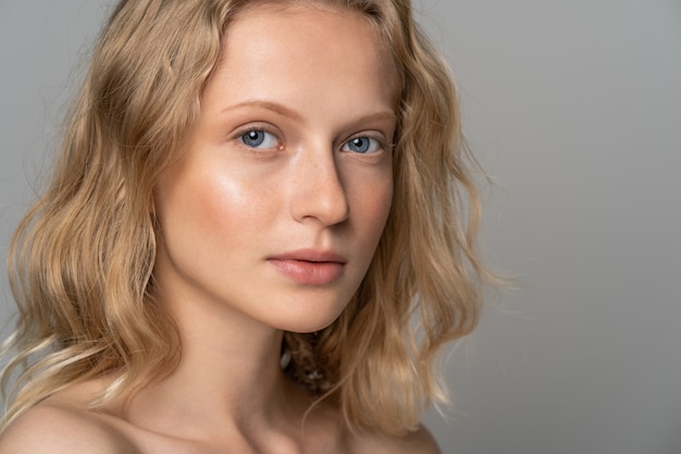 Young woman face with blue eyes, curly natural blonde hair and eyebrows