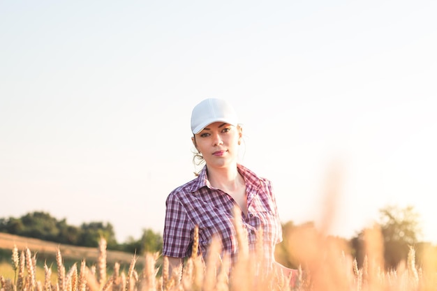 Young woman farmer works on a wheat field in the sun. Business woman plans her income in the field. Female agronomist with a tablet study the wheat crop in the agricultural field. Grain harvest.