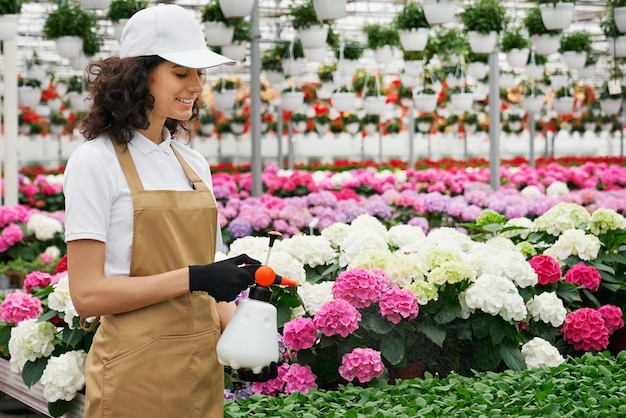 Young woman feeding beautiful flowers with polivizator