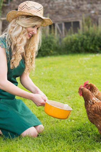 Giovane donna che alimenta il suo pollo