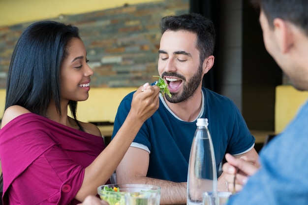 Foto la giovane donna alimenta l'insalata all'uomo