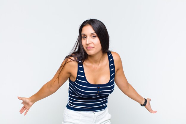 Young woman feeling clueless and confused, having no idea, absolutely puzzled with a dumb or foolish look